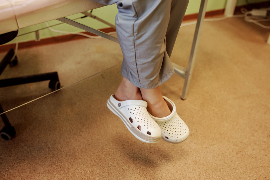 Εργαζόμενος σε νοσοκομείο ξεκουράζεται μετά από πολύωρη ορθοστασία, φορώντας άσπρα ανατομικά παπούτσια (σαμπό).